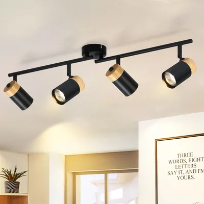 A ceiling light fixture with four adjustable spotlights, mounted on a track, in a room with a white ceiling and wall.