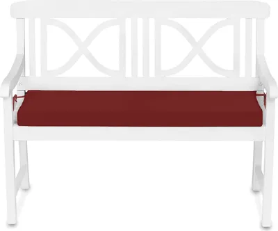 A white garden bench with a red cushion.