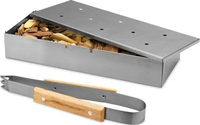 A stainless steel smoker box filled with wood chips and a pair of wooden-handled tongs are shown on a white background.