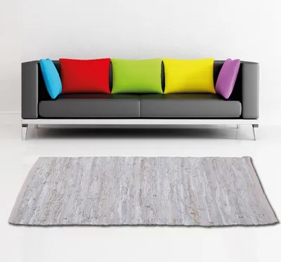 A modern living room setting with a black leather sofa and colorful cushions, and a rug in front of it.