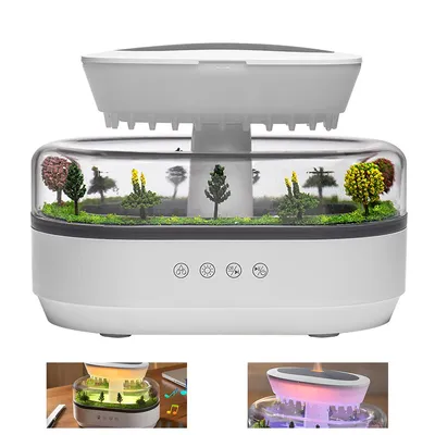 A white humidifier with a clear dome displaying a miniature landscape of trees and moss. The humidifier has several control buttons on its base and a white top. Two smaller inset images show the humidifier in use with lighting effects and music.