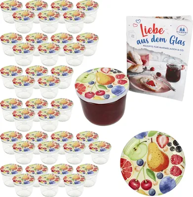 A set of small glass jars with fruit-themed lids, a recipe book, and a decorative plate, all arranged on a white background.