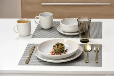 A table setting with plates, bowls, mugs, and cutlery.