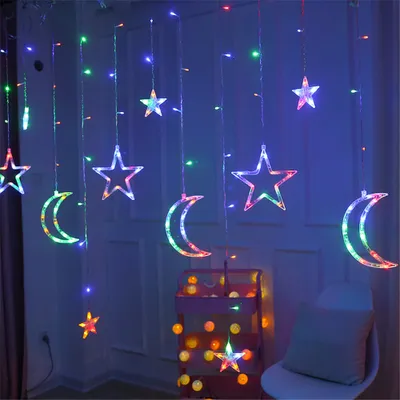 A string of LED lights shaped like stars and moons hanging against a blue wall.