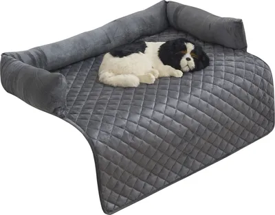 A gray quilted dog bed with a plush toy dog on it, set against a white background.