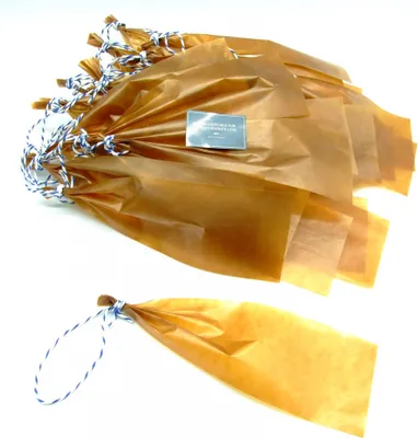 A pile of brown paper sausage casings tied with blue and white string, with one casing shown separately in the foreground.