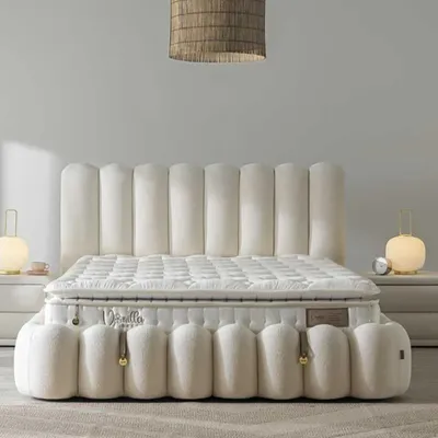 A bed with a mattress and topper is shown in a bedroom setting.