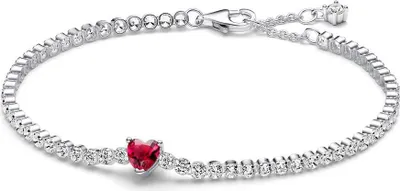 A silver tennis bracelet with a red heart-shaped stone in the center, displayed on a white background.