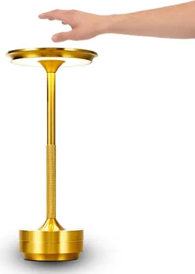 A hand reaching towards a golden LED table lamp.