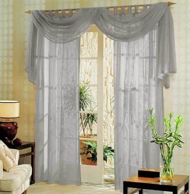 A room with a large window covered by gray sheer curtains.