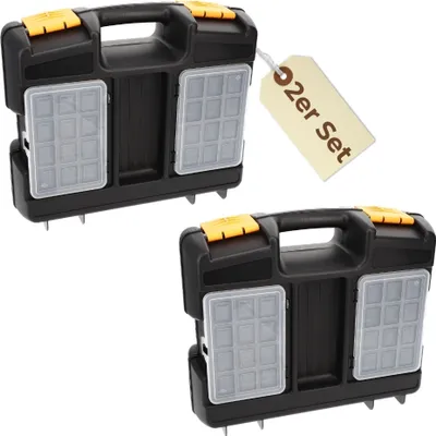 Two identical black toolboxes with yellow latches and clear compartment lids, presented on a white background. A beige tag with German text is attached to the upper toolbox.