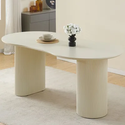 A cream-colored oval dining table with fluted pedestal legs, set in a room with a rug and a sideboard in the background.