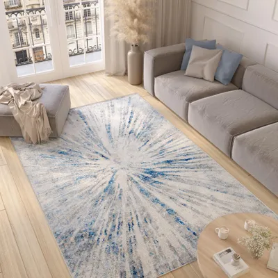 A living room scene with a modern rug, sofa, ottoman, and coffee table.