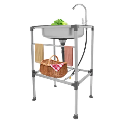 A freestanding kitchen sink with a faucet, a basket, and towels hanging on the side.