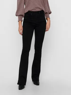 A person wearing black flared jeans and a brown sweater, shown from the waist down.