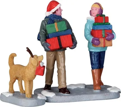 A Christmas-themed figurine set featuring two people and a dog carrying gifts.
