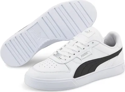 A pair of white Puma sneakers with black accents, shown from a slightly elevated angle with the sole of one shoe visible.