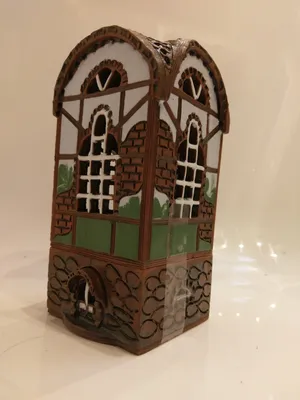 Das Keramikhaus ist in braunen, weißen und grünen Tönen gehalten, mit einem Fachwerk-Design.