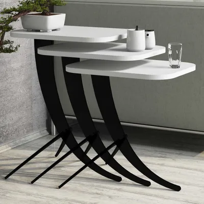 A set of three white nesting tables with black curved legs, displayed on a light-colored floor against a gray wall.