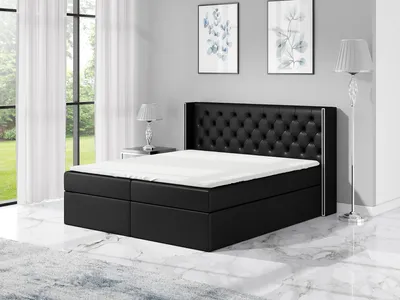 A bedroom scene with a black boxspring bed.