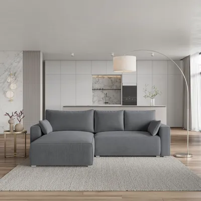 A modern living room with a gray sectional sofa, a kitchen in the background, and a floor lamp.