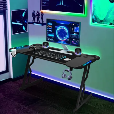 A gaming desk setup in a room with colorful LED lighting.