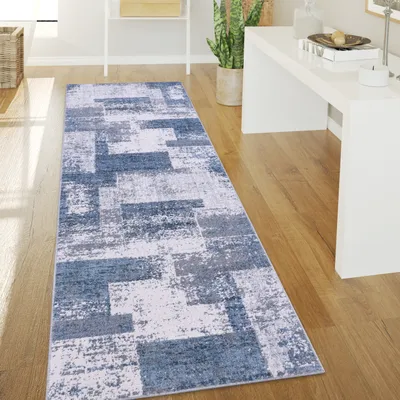 A hallway with a runner rug on a wooden floor, next to a white console table and a potted plant.
