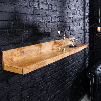 A wooden shelf mounted on a black brick wall, decorated with two candle holders and a glass globe with a bird inside.