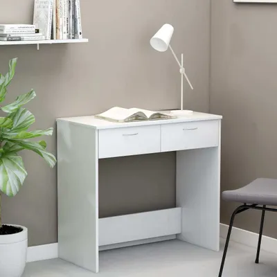 A white desk with a book and a lamp on it, in a room with a plant and a chair.
