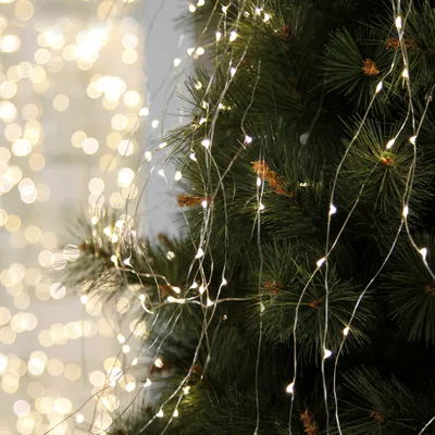 Close-up of LED fairy lights draped on a Christmas tree with a bokeh background.