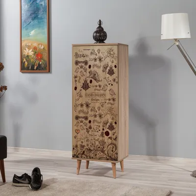 A tall, narrow cabinet with a decorative pattern stands in a room with a painting on the wall and a floor lamp.