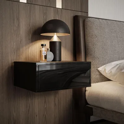 A modern bedroom nightstand with a black high-gloss drawer and a lamp, next to a bed with a textured headboard.