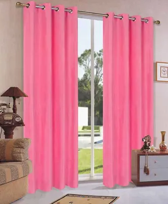 A room with pink curtains covering a window, a sofa, and a cabinet.