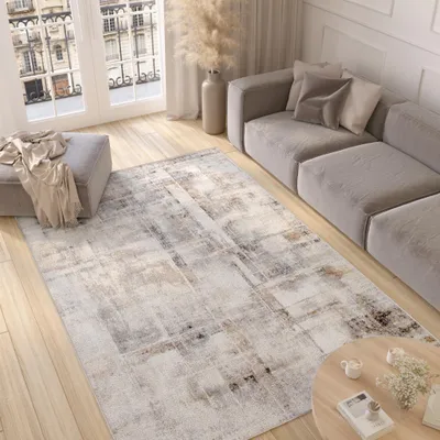 A modern living room with a sofa, rug, ottoman, and coffee table.