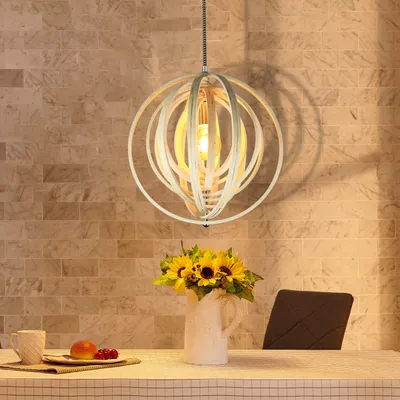 A dining table setting with a pendant light hanging above, a vase of sunflowers, and a cup and fruit on the table.