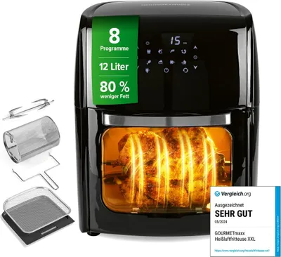 A black air fryer with a rotisserie chicken inside, shown with accessories on the side.