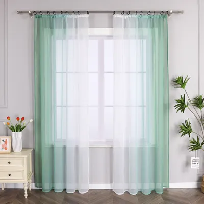 A window with sheer curtains, a bedside table with flowers and a picture, and a plant.
