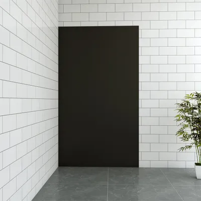 A corner of a room with white tiled walls and a dark rectangular panel in the center. A potted plant is visible on the right.