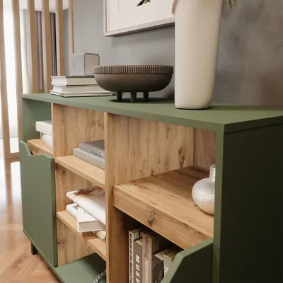 A close-up view of a green and wood-toned sideboard with books and decorative items on and inside it.