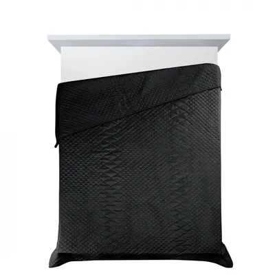 A black quilted blanket is laid out on a bed.