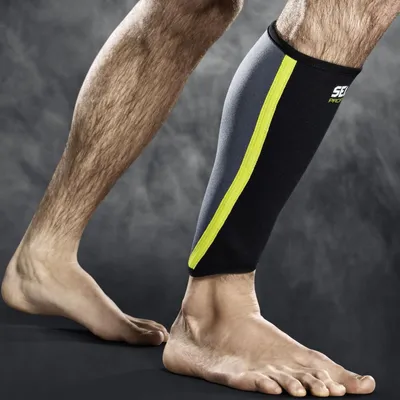 A person's legs are shown, with one leg wearing a black and gray calf compression sleeve with a yellow stripe.