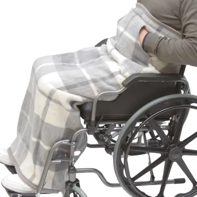 A person in a wheelchair is covered by a plaid blanket.