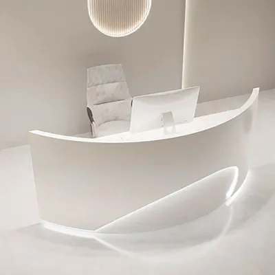 A modern, white reception desk with a curved design and integrated lighting, along with a computer monitor and a chair.