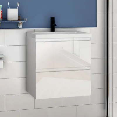 A white high-gloss bathroom vanity with a black faucet against a blue wall and white tiled background.