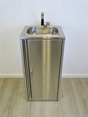 A stainless steel sink with a cabinet and faucet is shown against a plain white wall and wooden floor.
