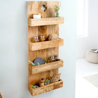 A wooden wall shelf with four tiers, decorated with small items like jars, a decorative sphere, and greenery.