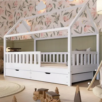 A child's bedroom with a white house-shaped bed, decorated with floral wallpaper and green wall panels. Toys are scattered on the floor.