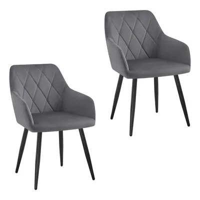 Two grey velvet dining chairs with diamond tufting and black metal legs against a white background.