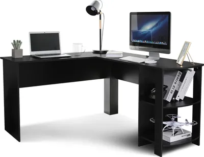 A black L-shaped desk with a laptop, monitor, lamp, and decorative items.