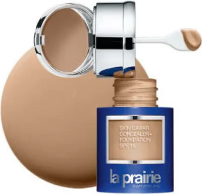 A bottle of La Prairie Skin Caviar Concealer Foundation SPF 15 is shown with its lid open and applicator extended, with a large swatch of foundation behind it.